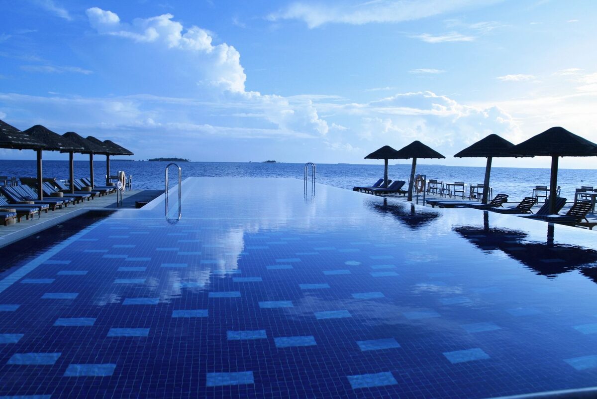 Infinity pool lined with sun loungers overlooking the Andaman Sea